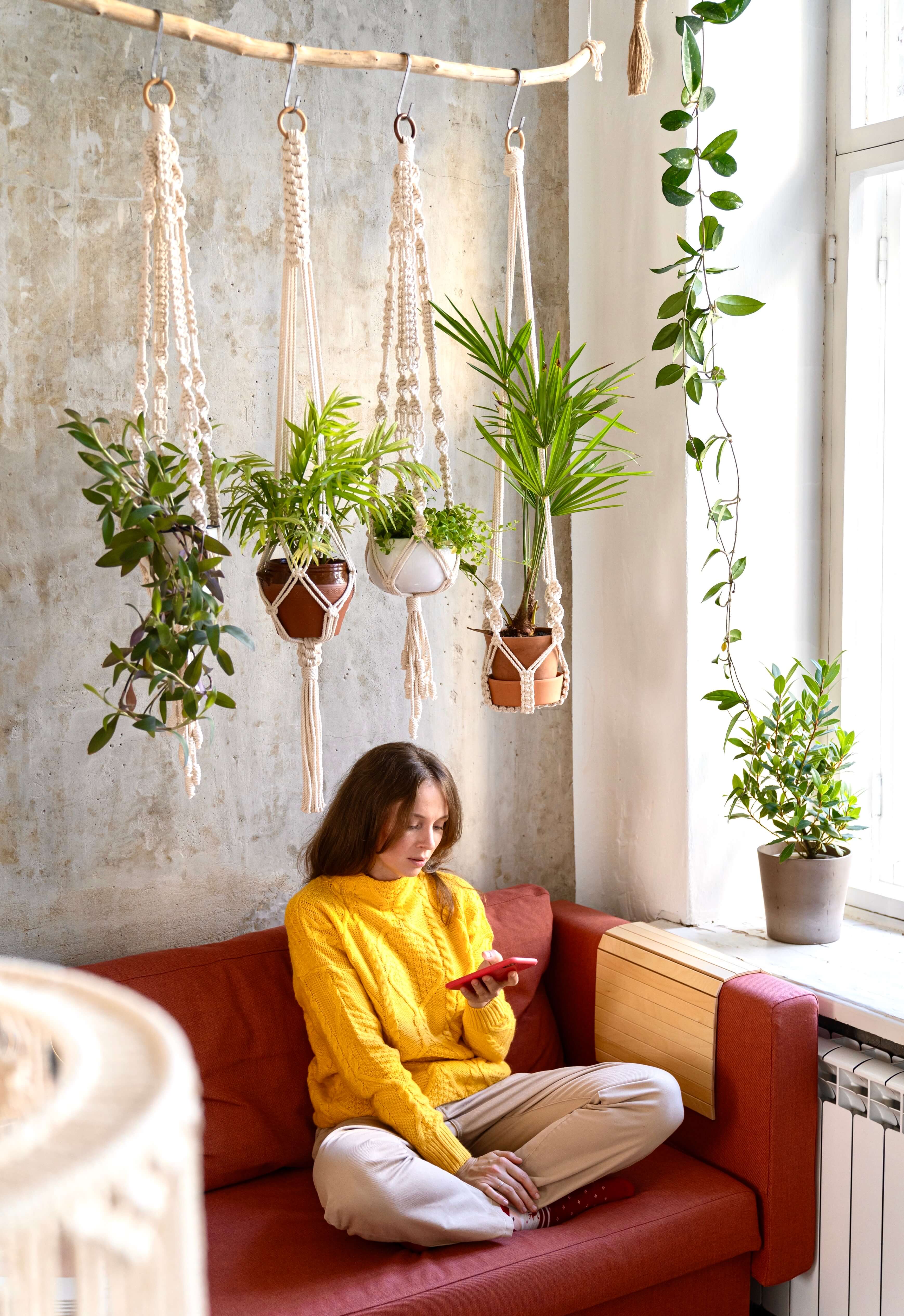 Zena pri okne s rastlinami na makrame